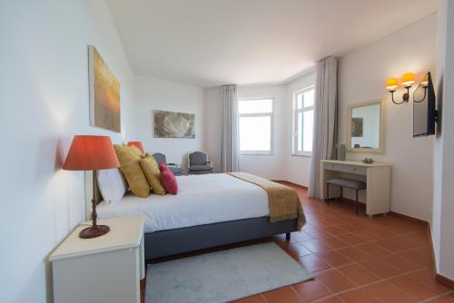 a bedroom with a bed and a desk with a lamp at Santa Clara Country Hotel in Santa Clara-a-Velha