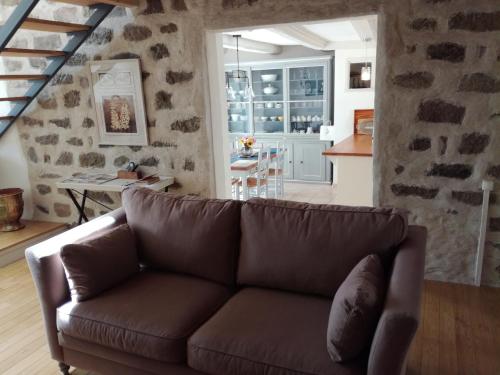 een woonkamer met een bruine bank en een keuken bij Gîte du Besset in Pradelles