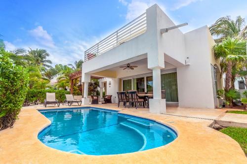 a villa with a swimming pool in front of a house at Villa Pura Vida - Spacious Oceanview with private pool - At Playacar Phase I in Playa del Carmen