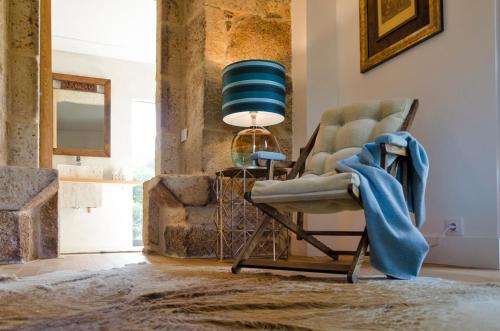 a room with a chair and a table with a lamp at A casa dos Parladoiros in Mos