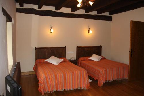 a bedroom with two beds with orange sheets at Casa Rural Bentazar in Elosu