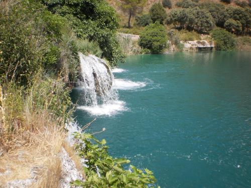 a river with a waterfall on the side of it at El Molino in Ruidera