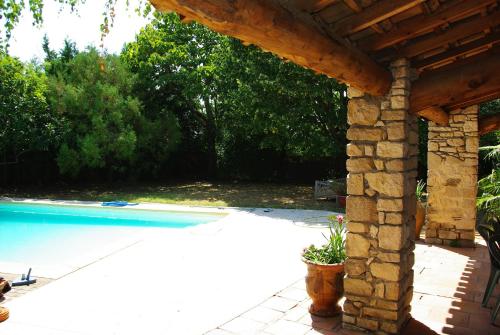 - une piscine avec une pergola en bois à côté dans l'établissement la maison bleue, à Vallon-Pont-dʼArc