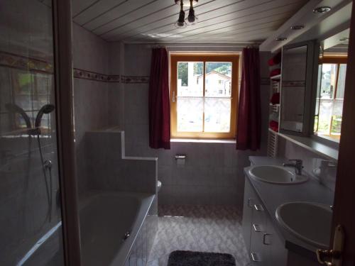 y baño con 2 lavabos, bañera y ducha. en Ferienwohnung Annele, en Hittisau