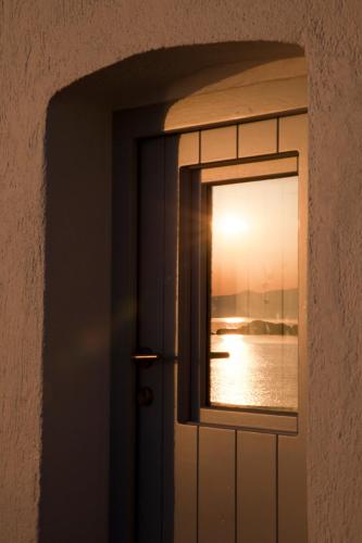 a door with a window looking out at the water at Traditional Waterfront House in Mandrakia
