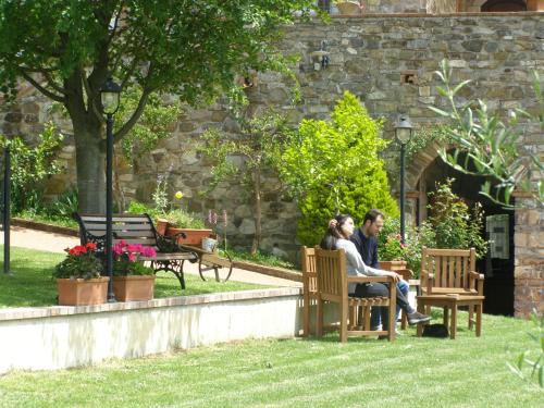 a couple sitting on benches in a garden at B&B Le Grazie in Piaggine