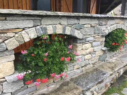 a stone wall with pink flowers in it at CHALET A CERESOLE REALE nel Parco Gran Paradiso in Ceresole Reale