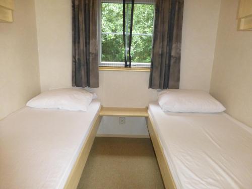 2 camas en una habitación pequeña con ventana en Vakantieverblijf Springendalsebeek, en Hezingen