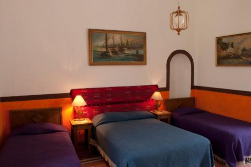 a bedroom with two beds and a red headboard at Posada San Francisco in Tequisquiapan