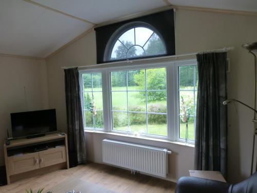 a living room with a large window and a television at Vakantieverblijf Springendalsebeek in Hezingen