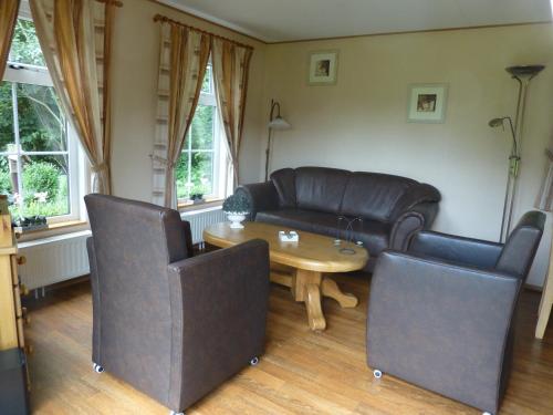 a living room with a leather couch and a table at Vakantieverblijf Springendalsebeek in Hezingen