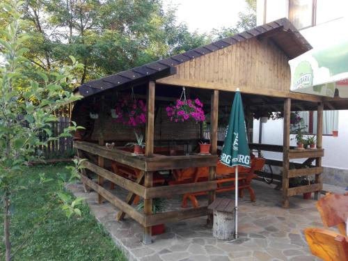 a wooden building with a table and an umbrella at Vila Madudu in Vălenii de Munte