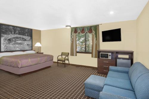 a bedroom with a bed and a couch and a tv at Super 8 by Wyndham Webster City IA in Webster City