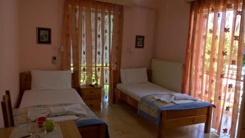 a room with two beds and a table and a window at Dimitra Pentaliou Rooms in Kamena Vourla