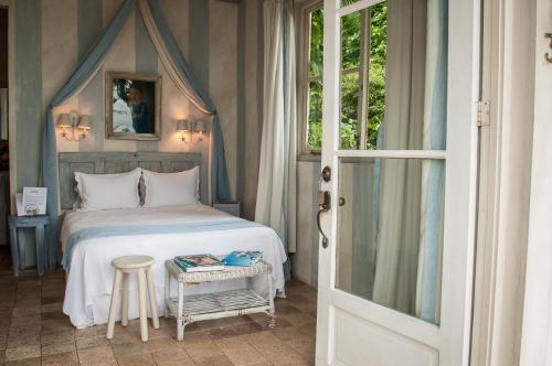 a bedroom with a bed and a table with a stool at Villa Caprichosa Boutique Hotels in Taboga