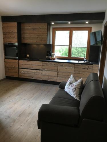 ein Wohnzimmer mit einem schwarzen Sofa und einer Küche in der Unterkunft Haus Schuchter in Pfunds