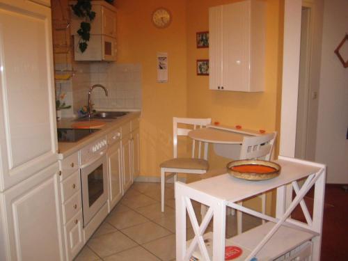 eine Küche mit weißen Schränken sowie einem Tisch und Stühlen in der Unterkunft Appartement Peers in Büsum