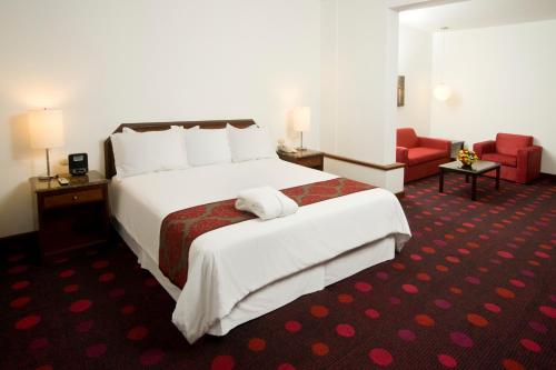 ein Hotelzimmer mit einem großen Bett und einem roten Stuhl in der Unterkunft Radisson San Isidro Hotel & Suites in Lima