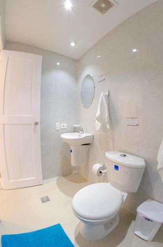 a white bathroom with a toilet and a sink at By The Sea Guest House in San Andrés