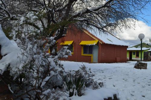 
a red brick building with a snow covered roof at Complejo Solitudine in Cacheuta
