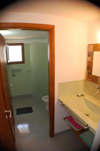 Un baño con inodoro, lavabo y espejo. en bella alegria, en Mar de las Pampas