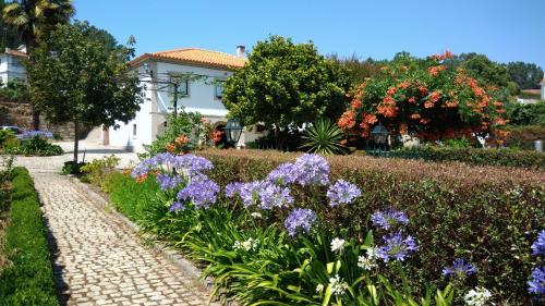 un jardín con flores púrpuras frente a una casa en THE RIVER HOUSE - Termas Guesthouse, en Termas de Sao Pedro do Sul