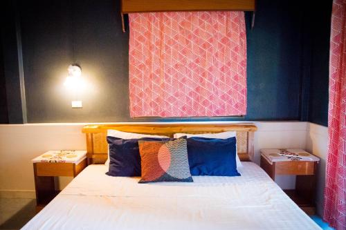 a bedroom with a bed with pillows and a wall at Oasis Yoga Bungalows in Ko Lanta
