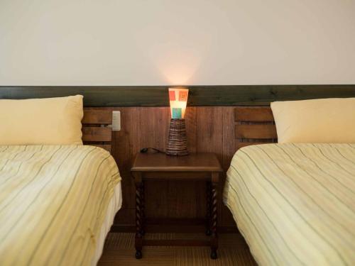 a lamp sitting on a table between two beds at Auberge Bonne Chere Raout in Onna