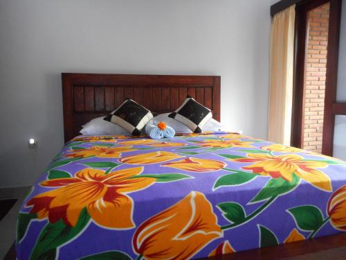 - un lit avec une couverture colorée et des fleurs dans l'établissement Pondok Indah Homestay, à Sidemen