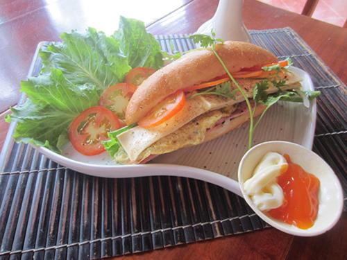 a sandwich on a plate with a salad and sauce at Gia Thanh Phu Quoc Guest House in Phu Quoc
