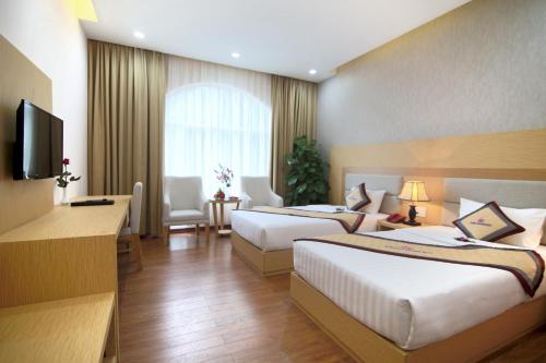 a hotel room with two beds and a television at Sai Gon Kim Lien Hotel Vinh City in Vinh