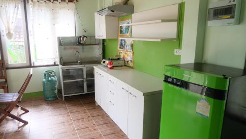 a green kitchen with white cabinets and a green refrigerator at Captan Home in Haad Chao Phao