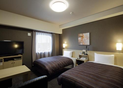 a hotel room with two beds and a flat screen tv at ​Hotel Route-Inn Ube​ in Ube