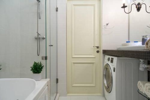 a bathroom with a shower and a sink and a washing machine at Lotos for You Apartments in Mykolaiv
