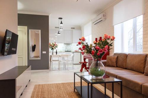 a living room with a couch and a vase of flowers on a table at Lotos for You Apartments in Mykolaiv