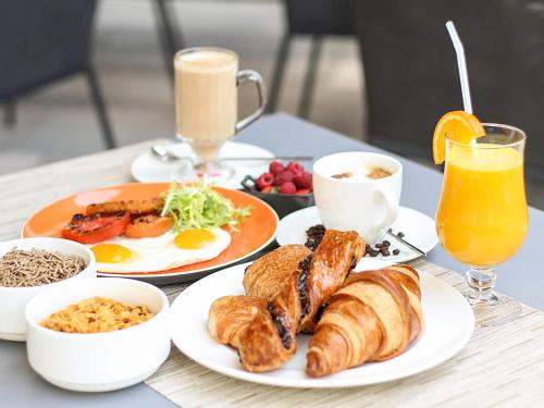 una mesa cubierta con platos de desayuno y zumo de naranja en Avangard Hotel, en Krasnodar