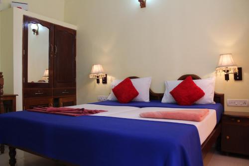 1 dormitorio con 2 camas y almohadas azules y rojas en Hotel Sea View Palace - the beach hotel en Kovalam
