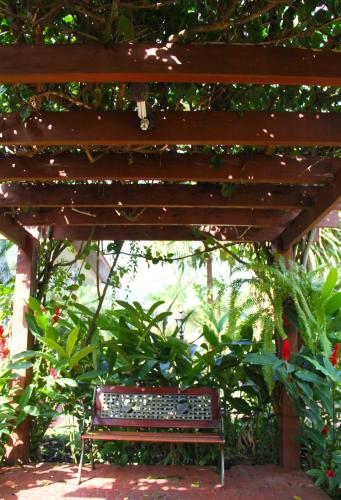 a bench sitting under a wooden pergola at Pousada Larimor in Boicucanga