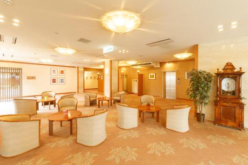 a lobby with tables and chairs and a clock at Hotel Amabile Maizuru in Maizuru