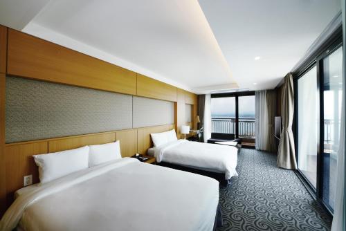 a hotel room with two beds and a large window at Ramada by Wyndham Gangwon Sokcho in Sokcho