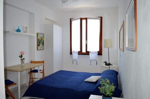 Un pequeño dormitorio con una cama azul y un escritorio. en House Libeccio by Holiday World, en Moneglia