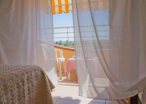 una camera da letto con finestra affacciata sull'oceano di Hotel Rivadoro-Spiaggia ombrellone e lettini inclusi-Piscina-Parcheggio a Martinsicuro