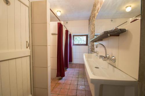 baño con lavabo blanco grande y cortinas rojas en Maison de la Vallee en Purnode