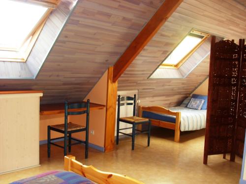 a attic room with a bed and two chairs at Le Stang in Le Croisty