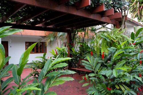 a bench sitting under a pergola in a garden at Pousada Larimor in Boicucanga