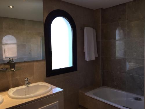 マニルバにあるResidencial Marina Duquesaのバスルーム(シンク、バスタブ付)、窓が備わります。