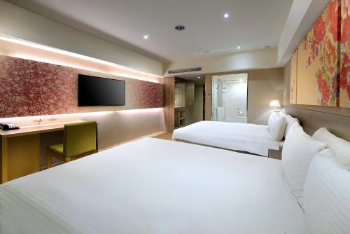 a hotel room with two beds and a television at Aeris International Hotel in Taichung