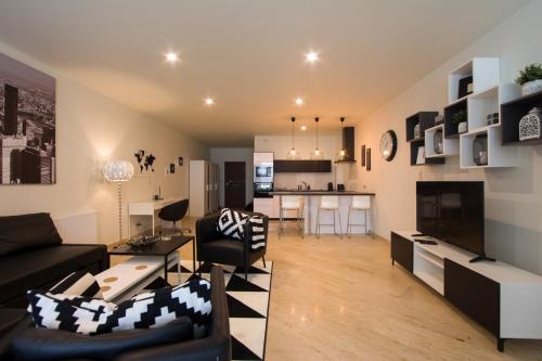 a living room with a couch and a table and a kitchen at Apart Madryt in Tarnobrzeg