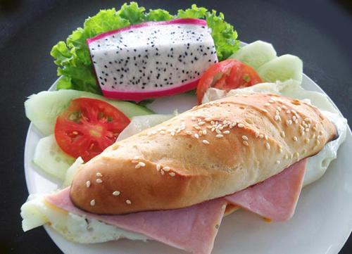 een sandwich met vlees en kaas en een salade op een bord bij Coconut Homes Khao Lak in Khao Lak