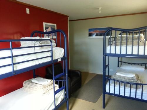 two bunk beds in a room with a red wall at Riverstone Lodge in Turangi